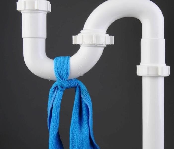 White plastic plumbing pipes with blue towel tied around piping
