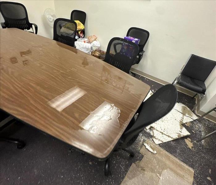 Water damage in a conference room with table and chairs and debris from damage